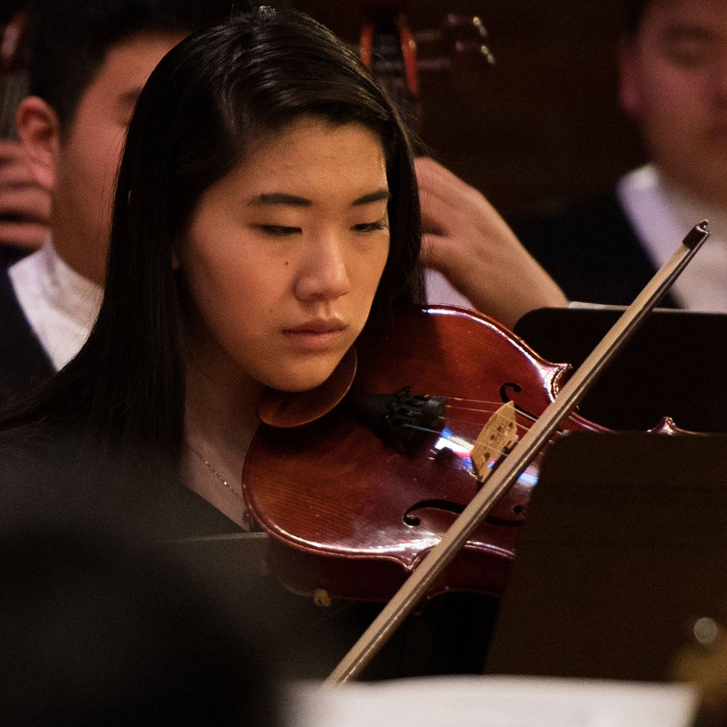 Woman playing a violin in an orchestra.