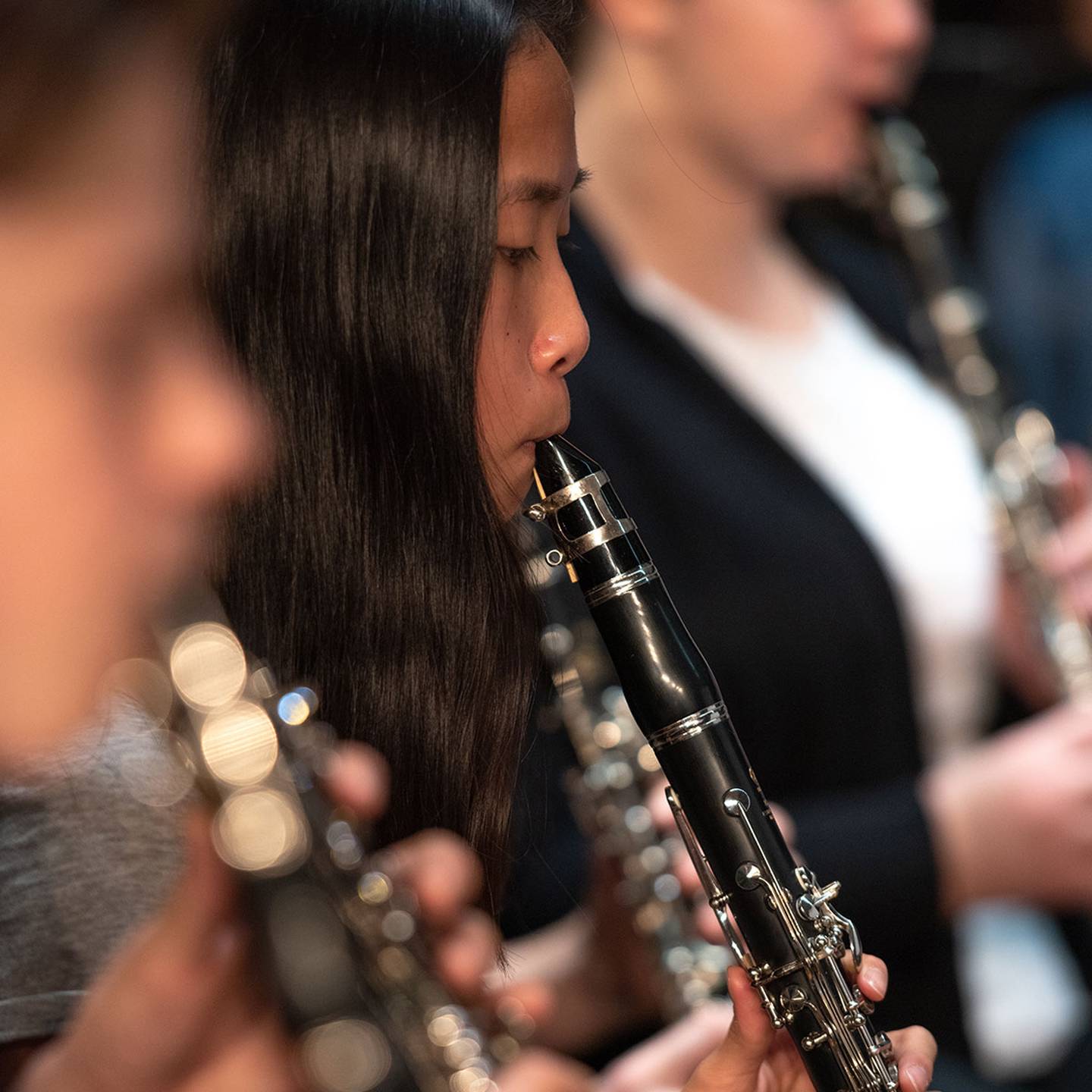 Close up of a woman playing a clarinet in concert.